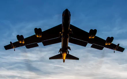 HD desktop wallpaper of a Boeing B-52 Stratofortress warplane bomber captured from below against a dusk sky, highlighting its military design and powerful silhouette.