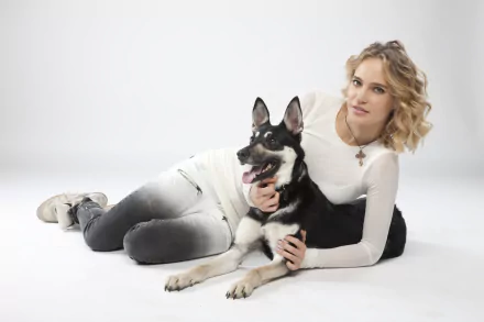 Blonde Russian pop singer reclining with her dog on a white studio background — 5K Ultra HD desktop wallpaper.