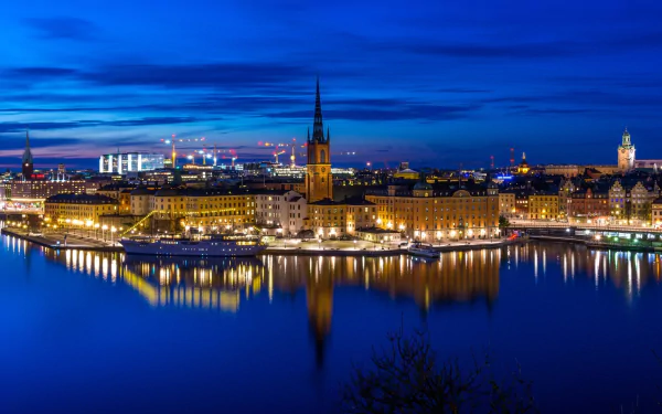Nighttime view of Stockholm’s illuminated skyline and waterfront in Sweden, reflected in calm water, captured in high definition.