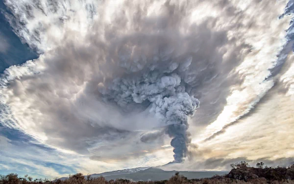A dramatic view of Mount Etna erupting, with dense smoke rising into a swirling cloud formation against a vivid sky, captured as an HD desktop wallpaper.