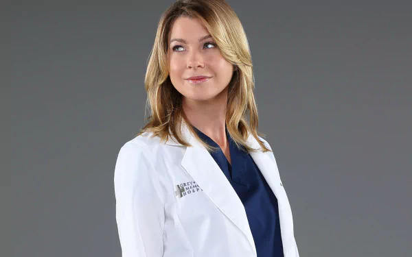 HD desktop wallpaper of a character from Grey's Anatomy in a white lab coat, with a neutral grey background.