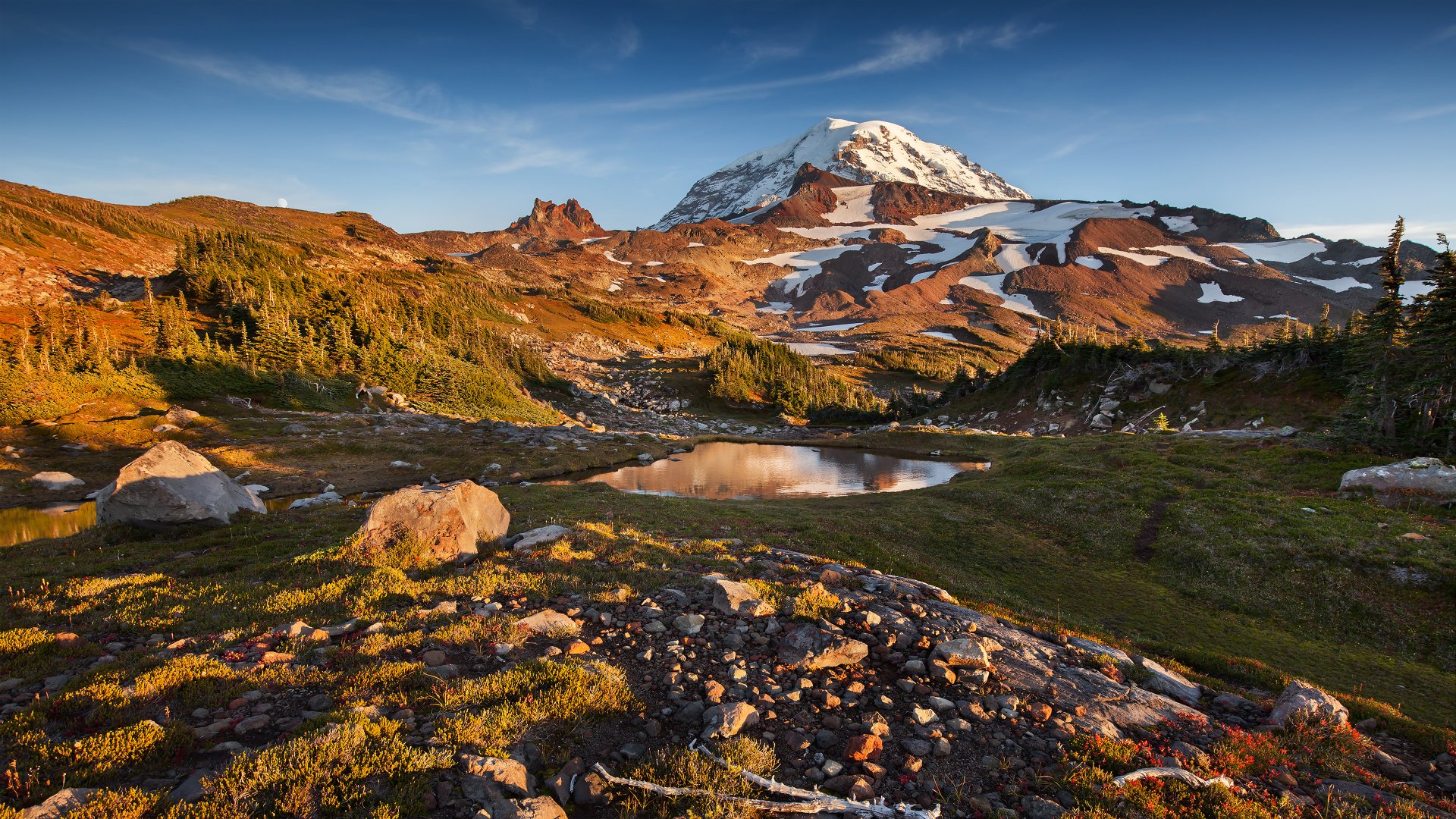 4K Ultra HD desktop wallpaper showcasing Mount Rainier with rugged mountain terrain, vibrant greenery, and a clear blue sky in a stunning natural landscape.
