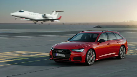 A red Audi A6 Avant driving on an airport runway with a private jet taking off in the background, showcased in 4K Ultra HD desktop wallpaper quality.