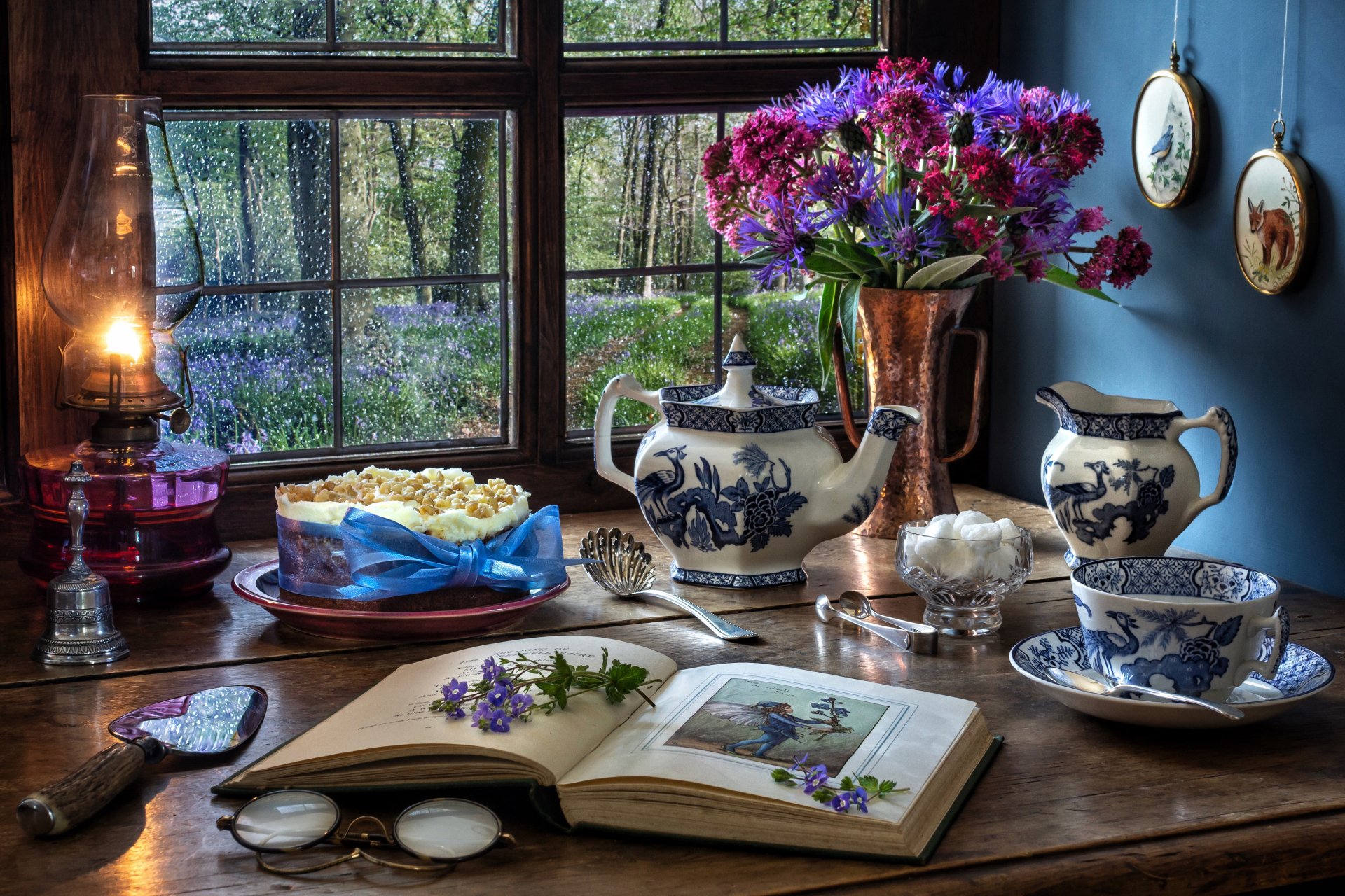 A 4K Ultra HD still life desktop wallpaper featuring a kerosene lamp, blue and white teapot and cup, a book with flowers, and a copper vase of purple blooms by a window.