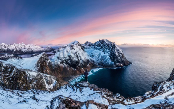 8K Ultra HD PC desktop wallpaper: panoramic winter photograph of snowy mountains along a rugged coastline where the ocean meets a pastel horizon.
