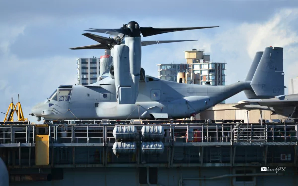 Bell Boeing V-22 Osprey military tiltrotor transport aircraft on a ship deck with city skyline under a cloudy sky — 2K Quad HD PC desktop wallpaper background