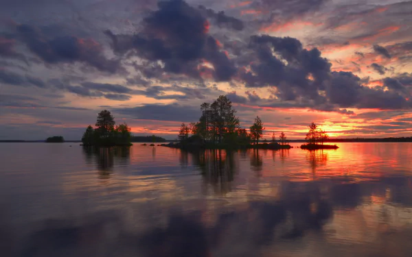 HD desktop wallpaper of a Finnish lake at sunset, featuring trees on small islands and dramatic clouds reflecting on the calm water, showcasing serene nature.