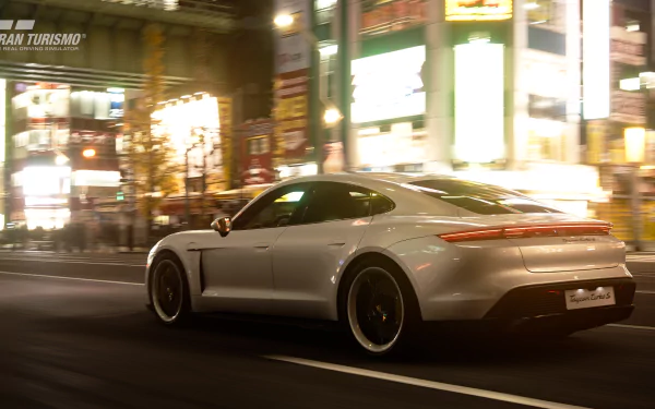 HD desktop wallpaper featuring a white Porsche Taycan Turbo S driving through a brightly lit city street at night, tagged with Porsche and video game Gran Turismo Sport.