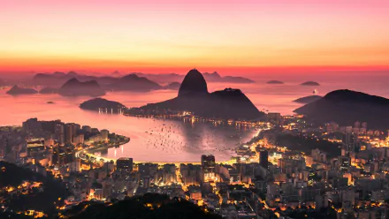4K Ultra HD PC desktop wallpaper: Rio de Janeiro cityscape at sunset, Sugarloaf Mountain rising above illuminated buildings and boats in Guanabara Bay.