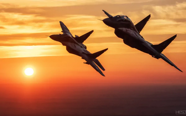 Two Mikoyan MiG-29 jet fighters bank over an orange sunset, military warplanes silhouetted against the sky — HD PC desktop wallpaper/background.
