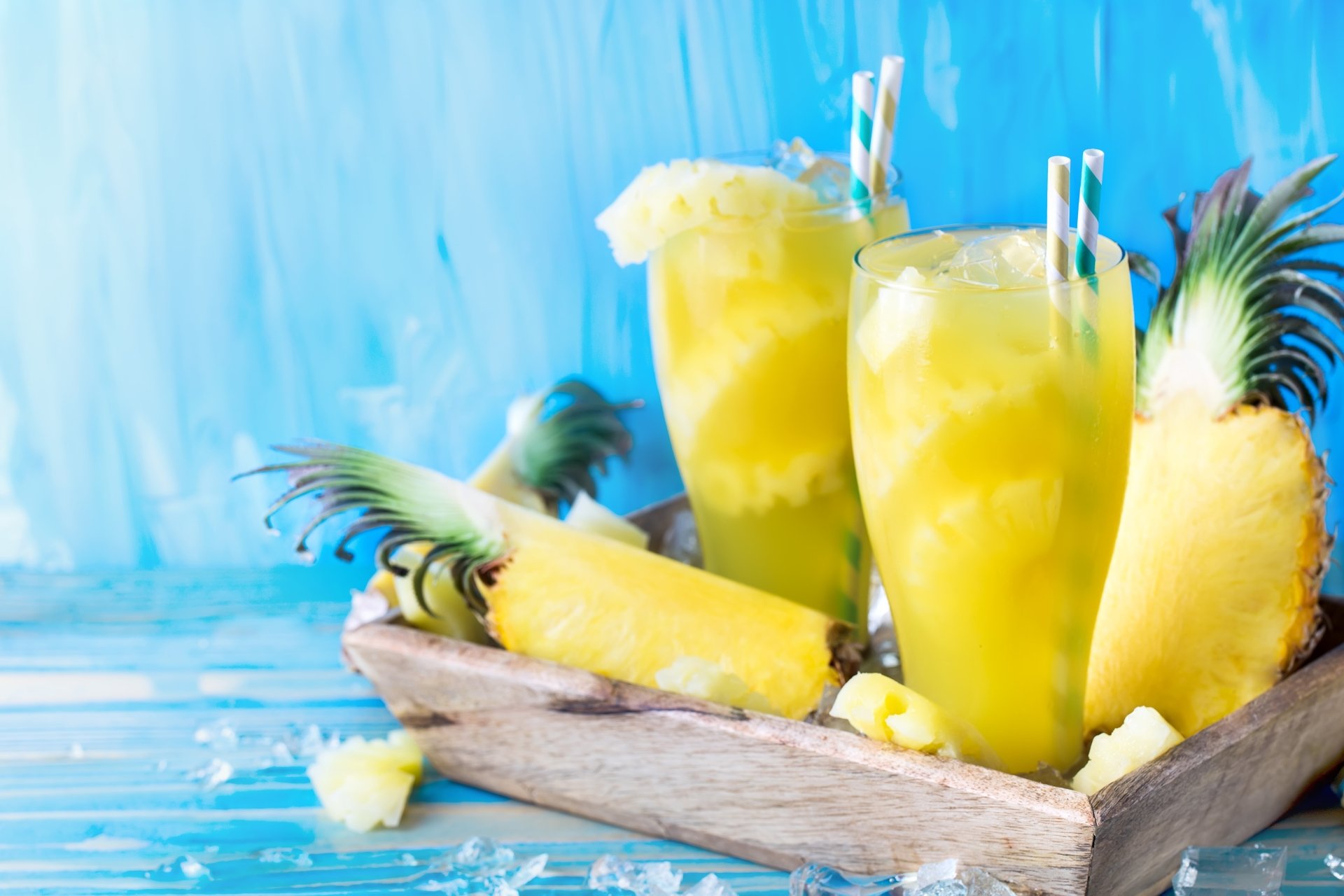 5K Ultra HD PC desktop wallpaper and background still life of pineapple cocktails: two glasses of pineapple juice with straws and wedges on a wooden tray against a blue backdrop.