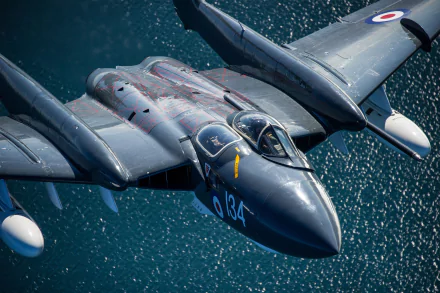 HD desktop wallpaper featuring a military de Havilland Sea Vixen jet fighter warplane in flight over water.