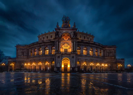 Ornate illuminated man-made building in Dresden, Germany at night, warm lights reflecting on a wet plaza — HD PC desktop wallpaper background.