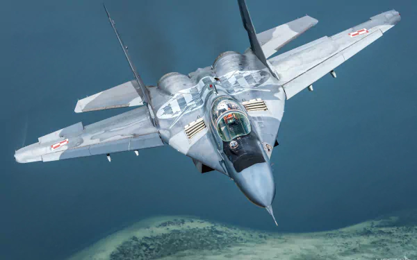 HD PC desktop wallpaper of a Mikoyan MiG-29 military jet fighter warplane in flight over coastline, forward view of the gray aircraft and cockpit.