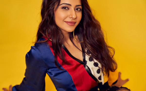 Portrait of a smiling brunette woman with long wavy hair and brown eyes against a bright yellow backdrop; 2K Quad HD PC desktop wallpaper.