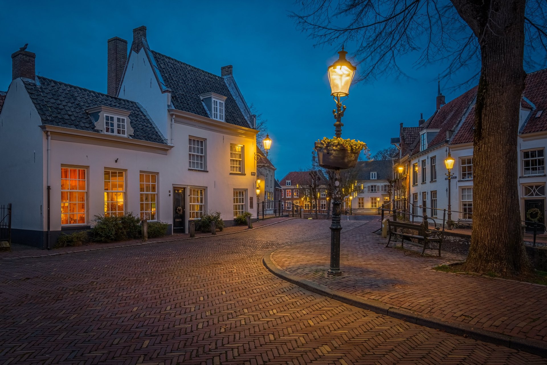 Evening view of a charming man-made street in the Netherlands, illuminated by warm street lamps, captured in 4K Ultra HD for a vivid desktop wallpaper.