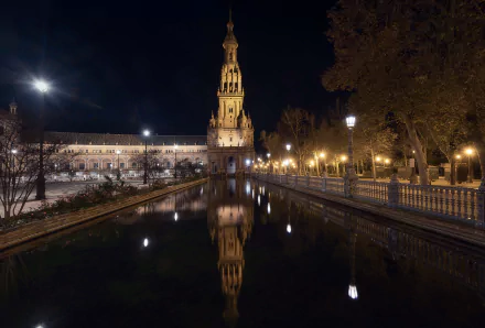 Night view of Plaza de España in Andalusia, showcasing illuminated architecture reflected in calm water, captured as an HD PC desktop wallpaper.