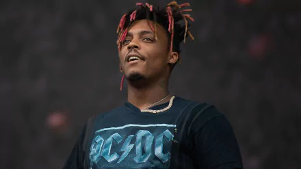 A vibrant HD desktop wallpaper featuring Juice Wrld performing, showcasing his energetic presence and unique style in the world of music.