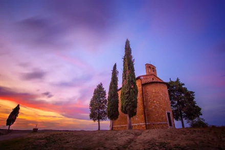 HD desktop wallpaper of a small round chapel and cypress trees at sunset in Tuscany, Italy — serene religious landscape background