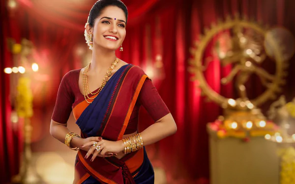 Bollywood actress Ruhani Sharma in a vibrant saree with gold jewelry and lipstick, smiling warmly against a rich red background with artistic depth of field.