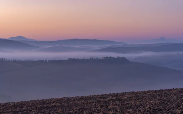 Foggy Tuscan landscape at dawn with layered hills under a pastel sky, captured in stunning 4K Ultra HD photography.