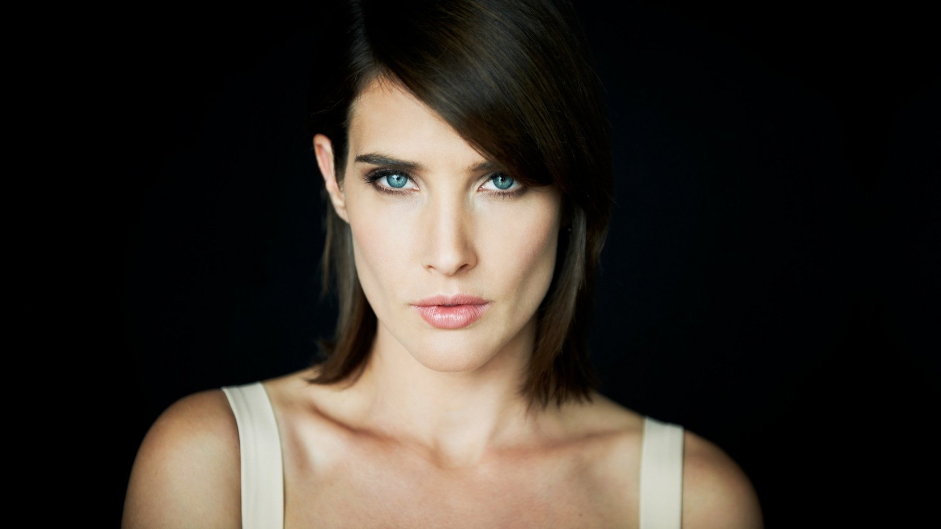 HD desktop wallpaper featuring a close-up portrait of actress Cobie Smulders with striking blue eyes against a dark background.