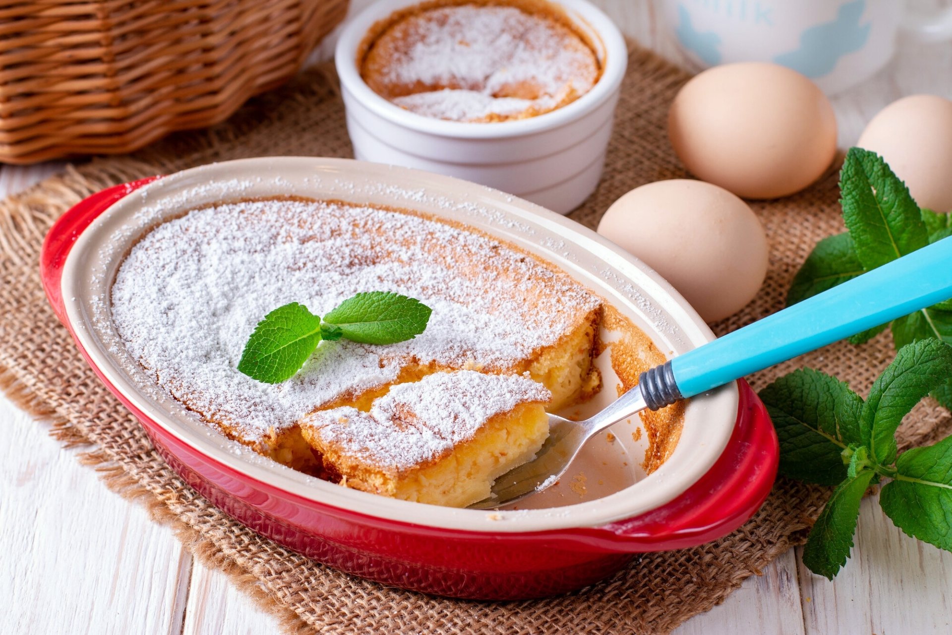 HD PC desktop wallpaper showing a baked pie dusted with powdered sugar, mint garnish, eggs and ramekins nearby — a baking food scene.