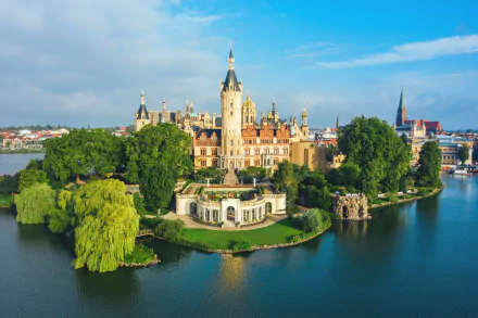 Aerial view of Schwerin Palace, a man-made castle on an island surrounded by a river in Germany, under a bright blue sky.