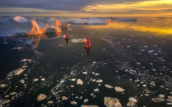 HD landscape photography of boats sailing through icy waters near towering icebergs in Greenland at sunset, with a serene ocean and scattered ice floes.