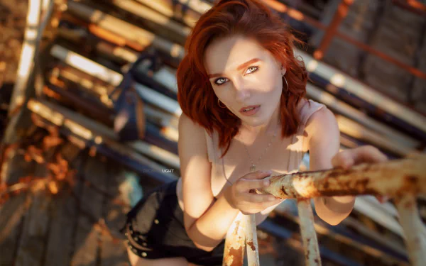 HD desktop wallpaper featuring redhead model Maria Larina looking up through sunlit metal scaffolding with warm shadows and urban textures.