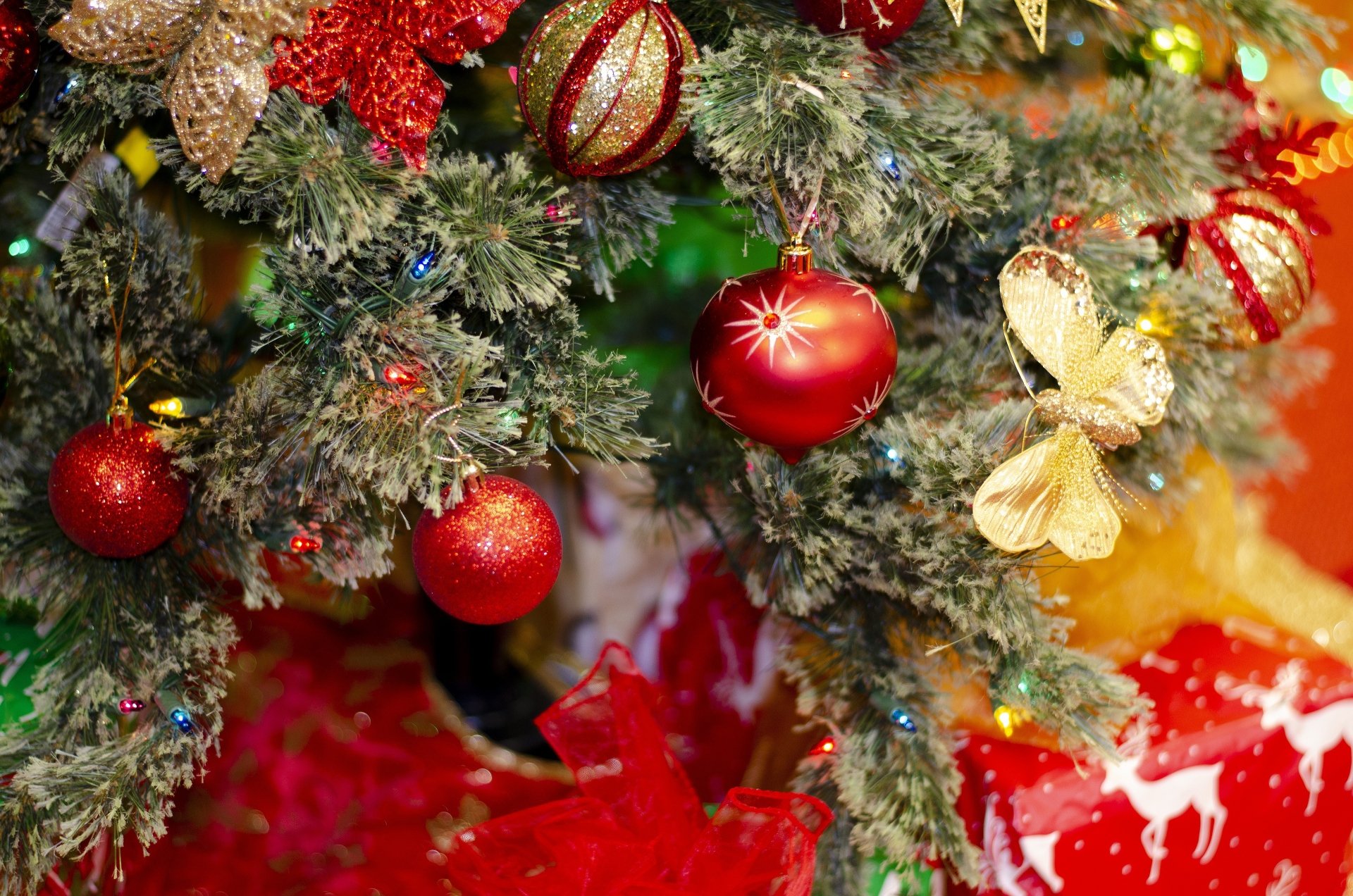 Close-up of a decorated Christmas tree with red and gold ornaments and butterflies, captured in vibrant 4K Ultra HD for a festive PC desktop wallpaper.