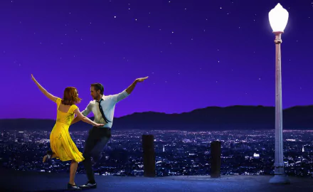 Emma Stone and Ryan Gosling dancing at night against a starry purple sky backdrop in a scene from the movie “La La Land.” The image is a HD desktop wallpaper and background.