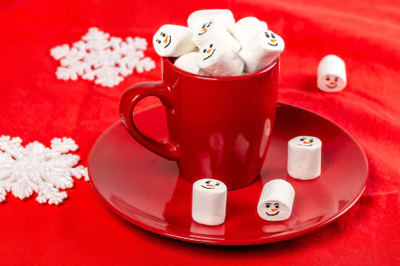 4K Ultra HD PC desktop wallpaper still life: red cup and saucer filled with marshmallow snowman faces on red cloth, white snowflake decorations.