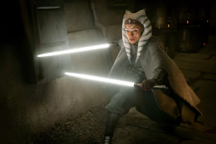 Ahsoka Tano from Star Wars: The Mandalorian, wielding dual white lightsabers in a dim stone corridor — HD PC desktop wallpaper/background.
