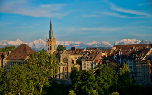 4K Ultra HD view of Bern, Switzerland, showcasing historic man-made architecture against a backdrop of the Alps under a clear blue sky.