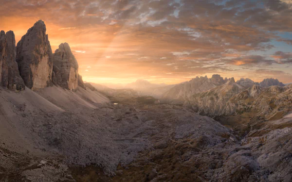 Sunrise over the rugged peaks of Tre Cime di Lavaredo in the Dolomites, captured in stunning 4K Ultra HD with a dramatic sky and expansive rocky landscape.