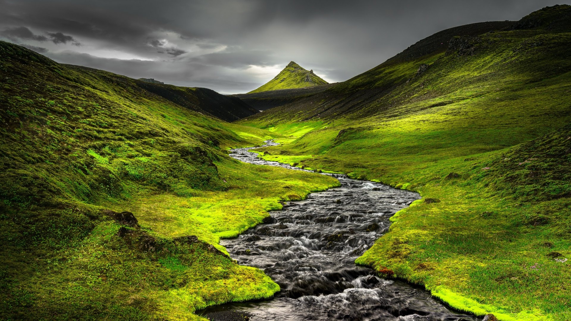 4K Ultra HD desktop wallpaper showcasing a vibrant green landscape with a flowing river winding through hills under a cloudy sky.