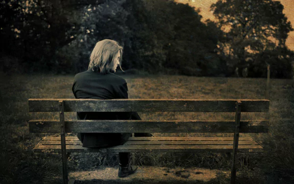 HD desktop wallpaper featuring a person sitting alone on a bench, set against a serene natural backdrop, creating a contemplative mood.