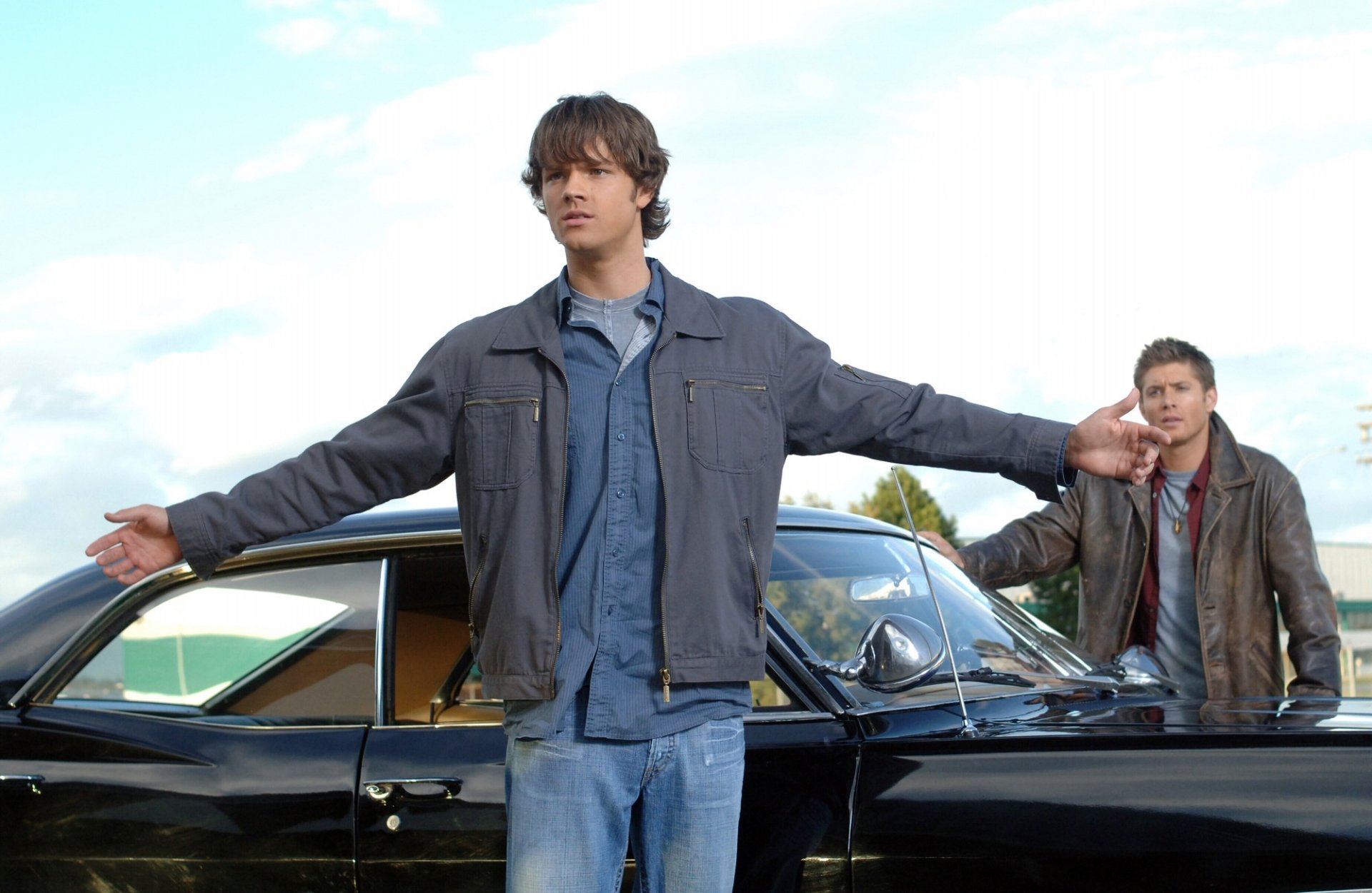 HD PC desktop wallpaper featuring Sam Winchester (Jared Padalecki) and Dean Winchester (Jensen Ackles) from the TV show Supernatural standing by their iconic black car.
