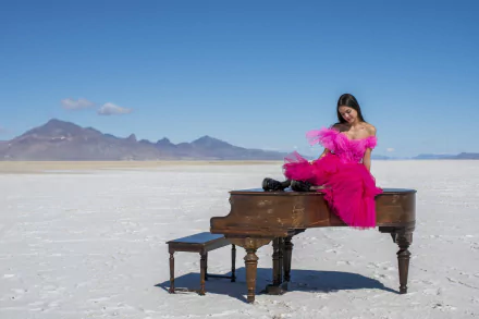 HD wallpaper of Olivia Rodrigo from High School Musical: The Musical: The Series, posing at a piano on a salt flat.