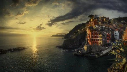 Sunset over the colorful cliffside village of Manarola in Cinque Terre, with calm water reflecting golden light, captured in a vibrant HD desktop wallpaper.