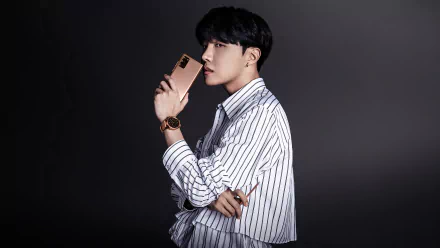 J-Hope (Jung Hoseok) of BTS poses in a striped shirt holding a smartphone, captured in a 4K Ultra HD music-themed PC desktop wallpaper.
