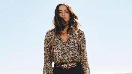 Portrait of Cuban actress Ana de Armas with green eyes and brunette hair, captured in 4K Ultra HD quality against a clear sky background.