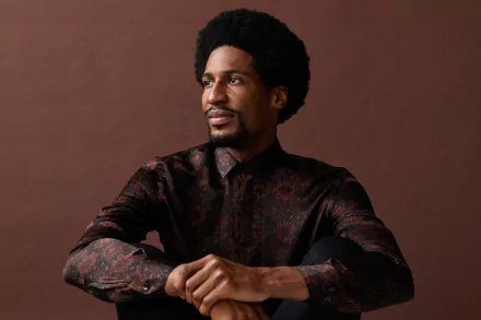 HD desktop wallpaper featuring a thoughtful person in a patterned shirt, posing against a brown background.