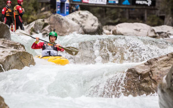 HD wallpaper of a kayaker navigating turbulent white water rapids with spectators watching from the shore.