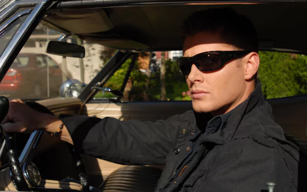 Dean Winchester, played by Jensen Ackles in Supernatural, sits confidently in a car wearing sunglasses; HD PC desktop wallpaper and background.