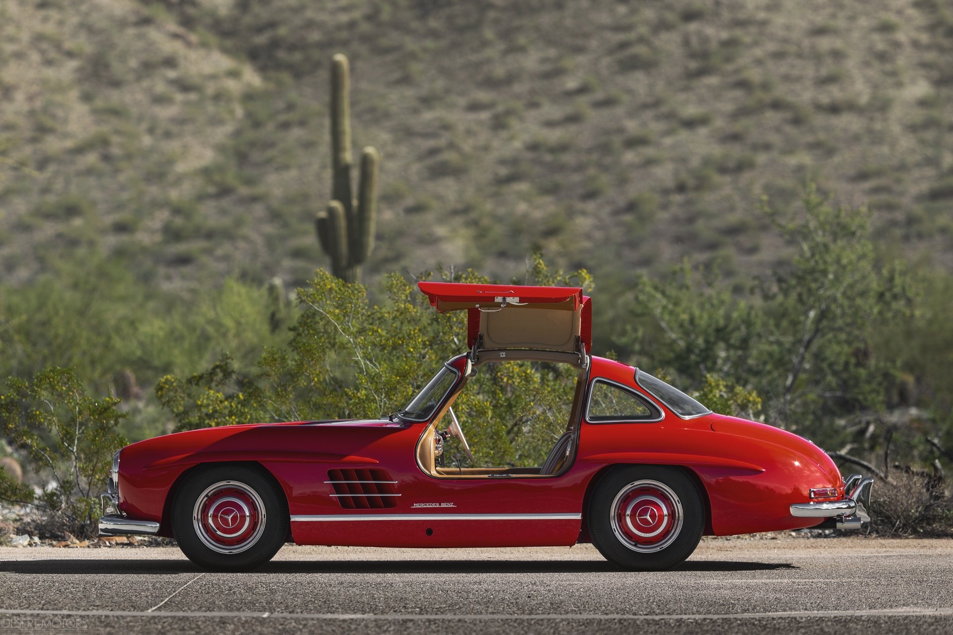 Red Mercedes-Benz 300SL gullwing car parked by desert roadside, classic Mercedes-Benz vehicle in 4K Ultra HD PC desktop wallpaper background.