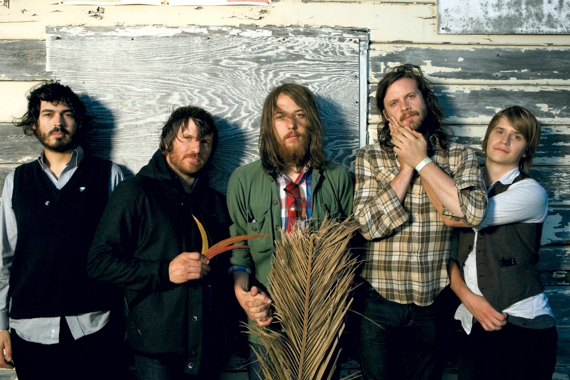 HD desktop wallpaper featuring the band Fleet Foxes, posing with a rustic backdrop.