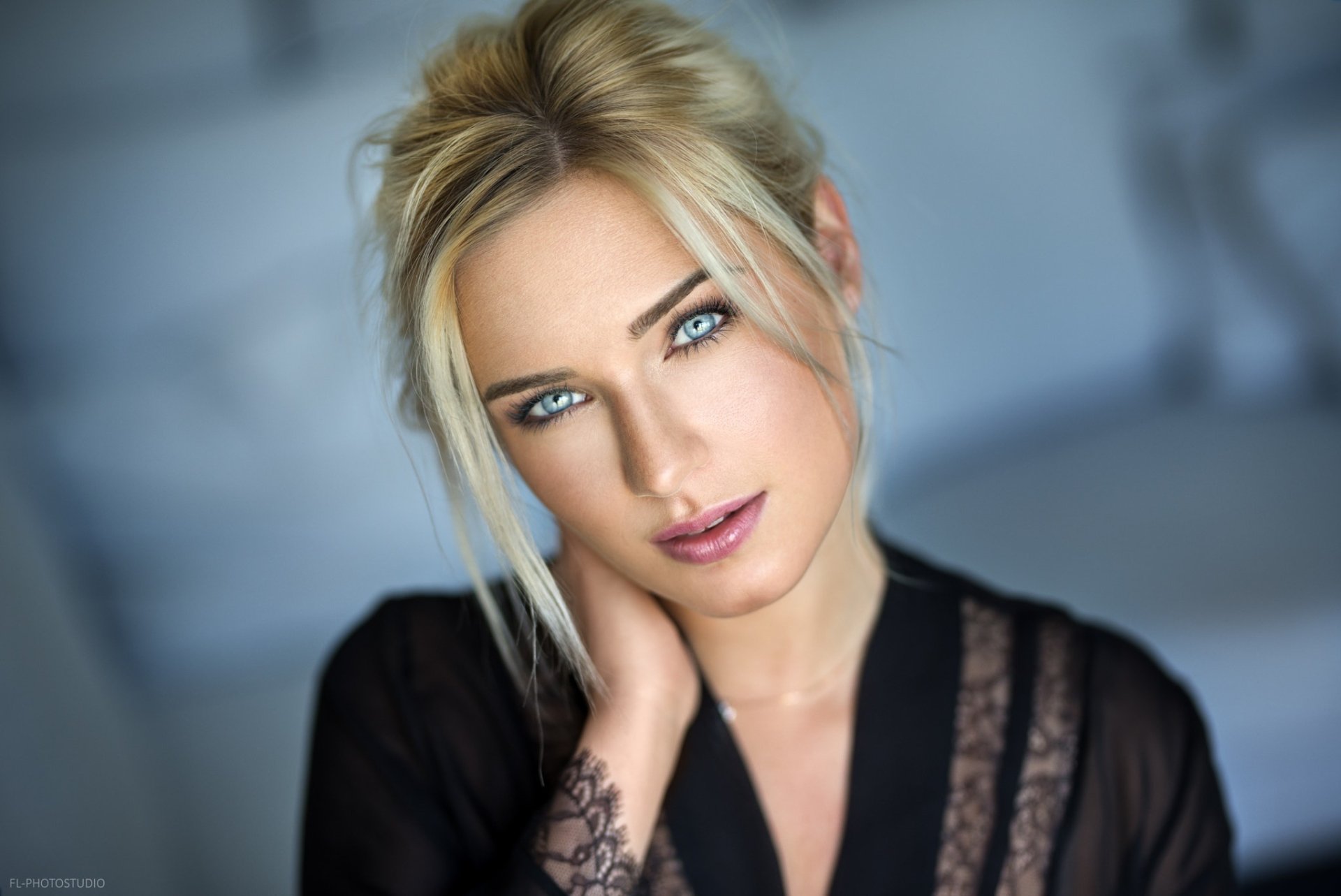 HD desktop wallpaper featuring a close-up portrait of model Eva Mikulski with blonde hair, striking blue eyes, and a soft expression against a blurred background.