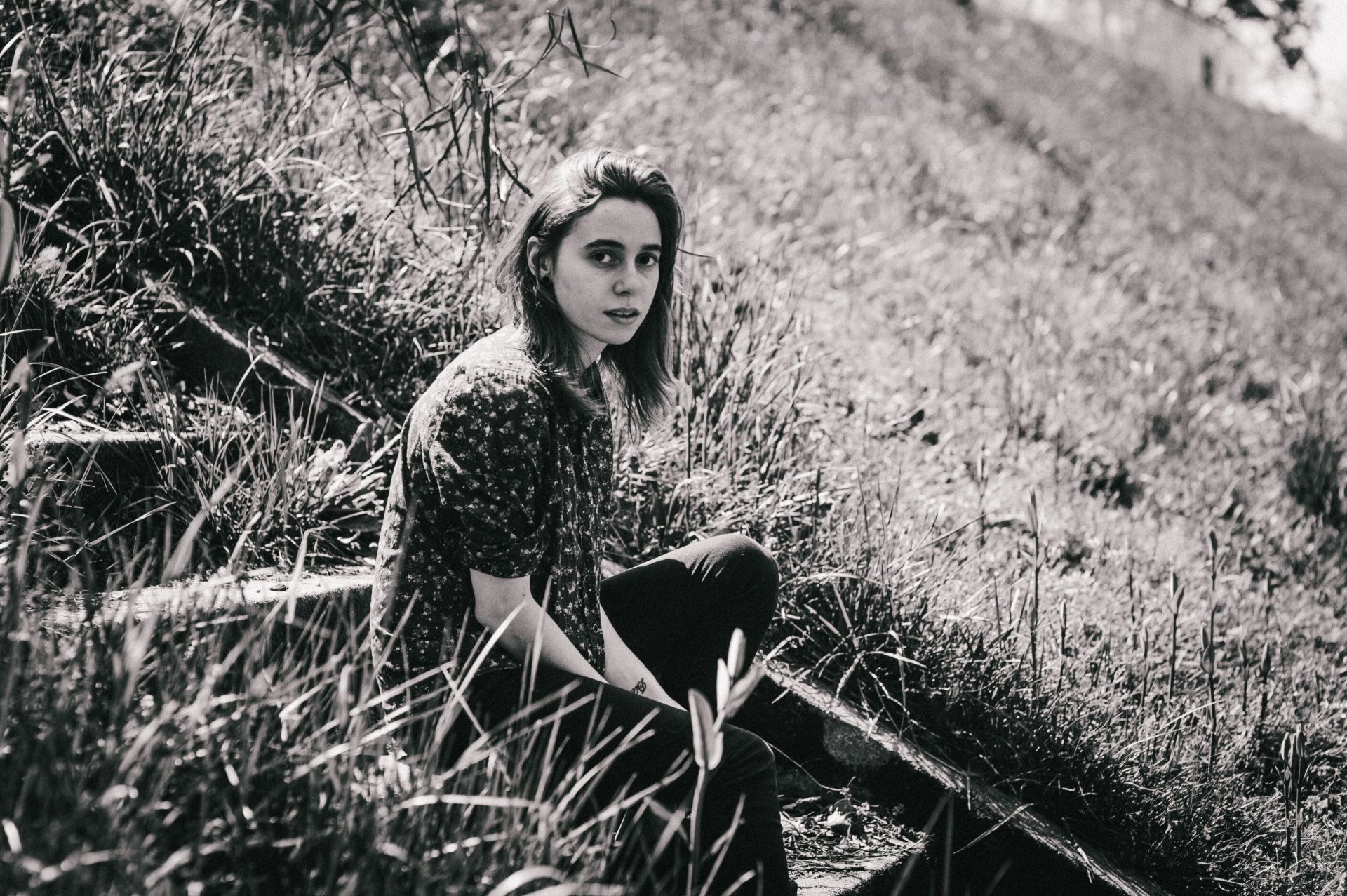 HD desktop wallpaper featuring a monochrome image of a person sitting on steps amidst grassy terrain, tagged with Julien Baker.